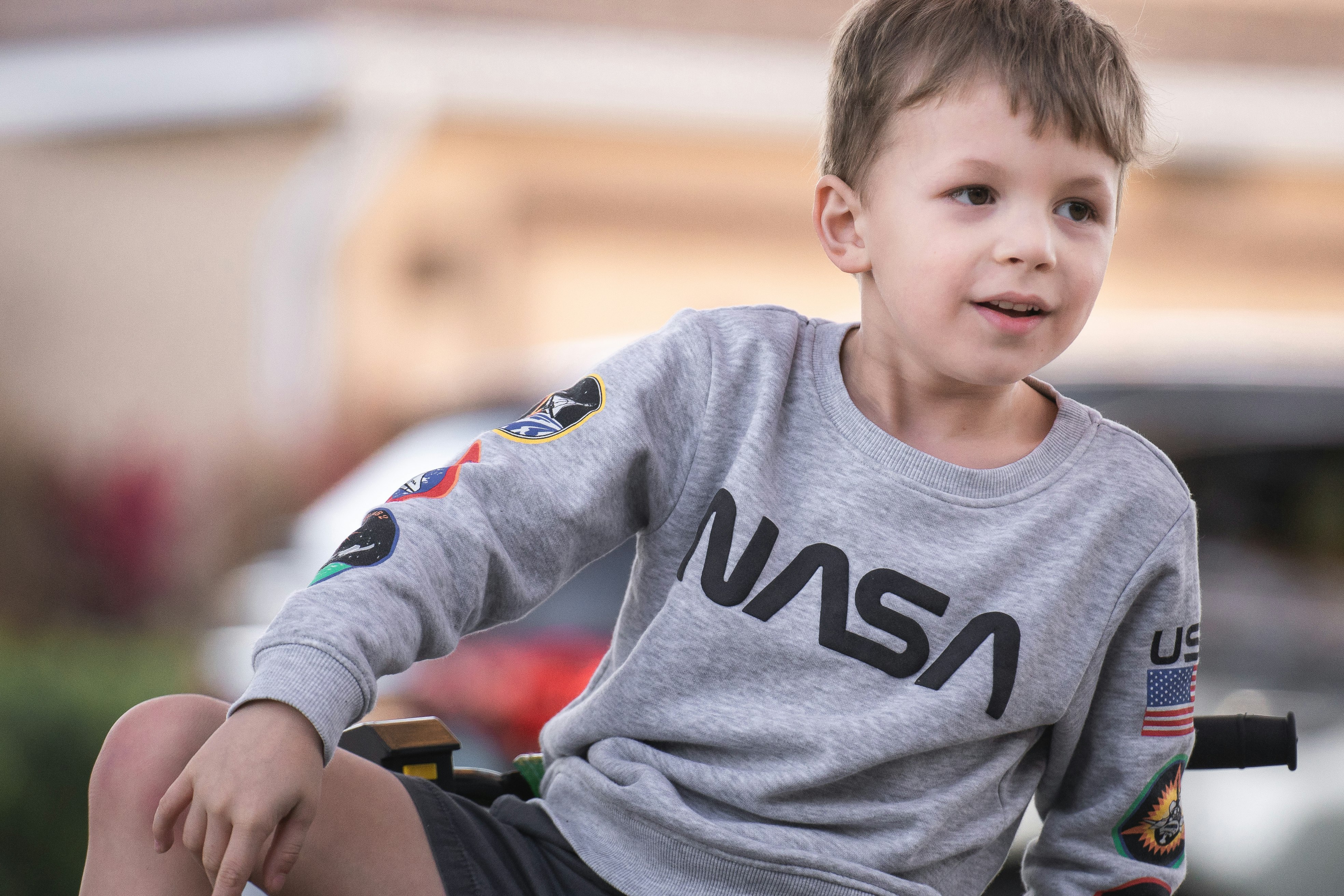 boy in gray crew neck long sleeve shirt sitting on green and black wheelchair